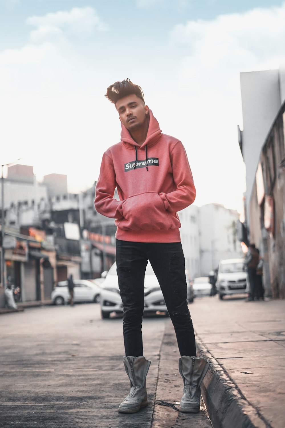 man in red pullover hoodie standing on street during daytime