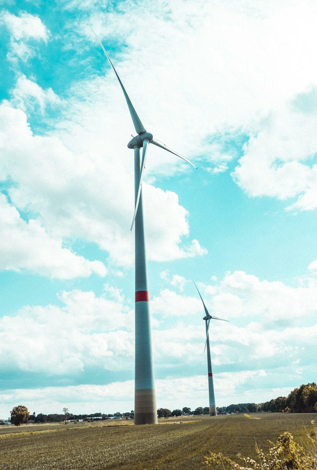 white wind turbine under blue sky and white clouds during daytime