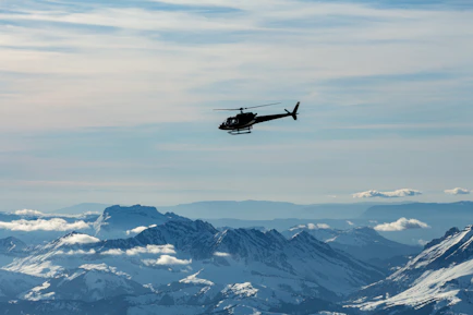 A helicopter soaring above the snow-capped peaks of the Himalayas during a clear sunrise.