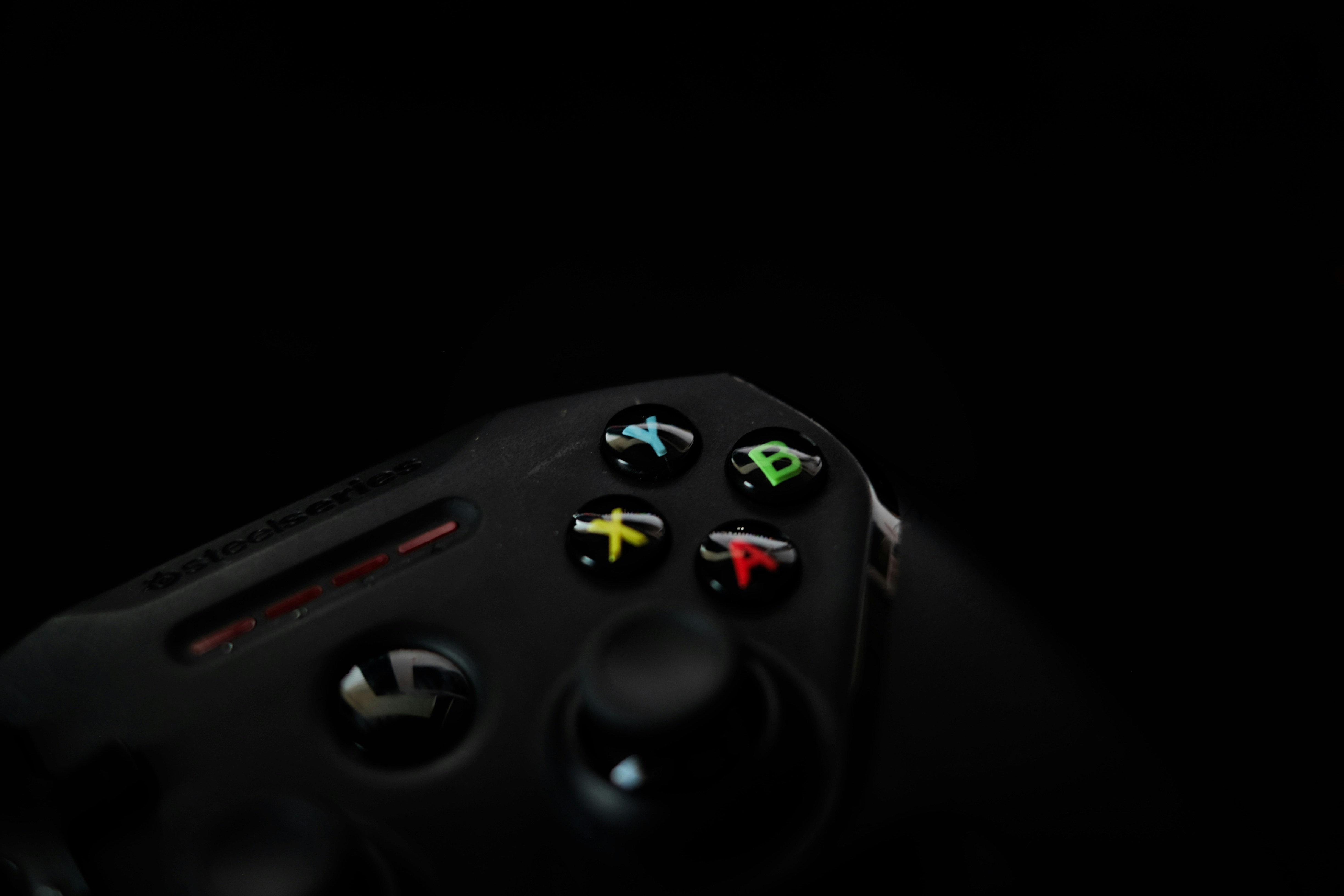 Close-up of a black video game controller with colorful buttons.