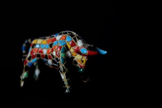 A vibrant digital illustration of a bull in dynamic motion with red and gold accents.