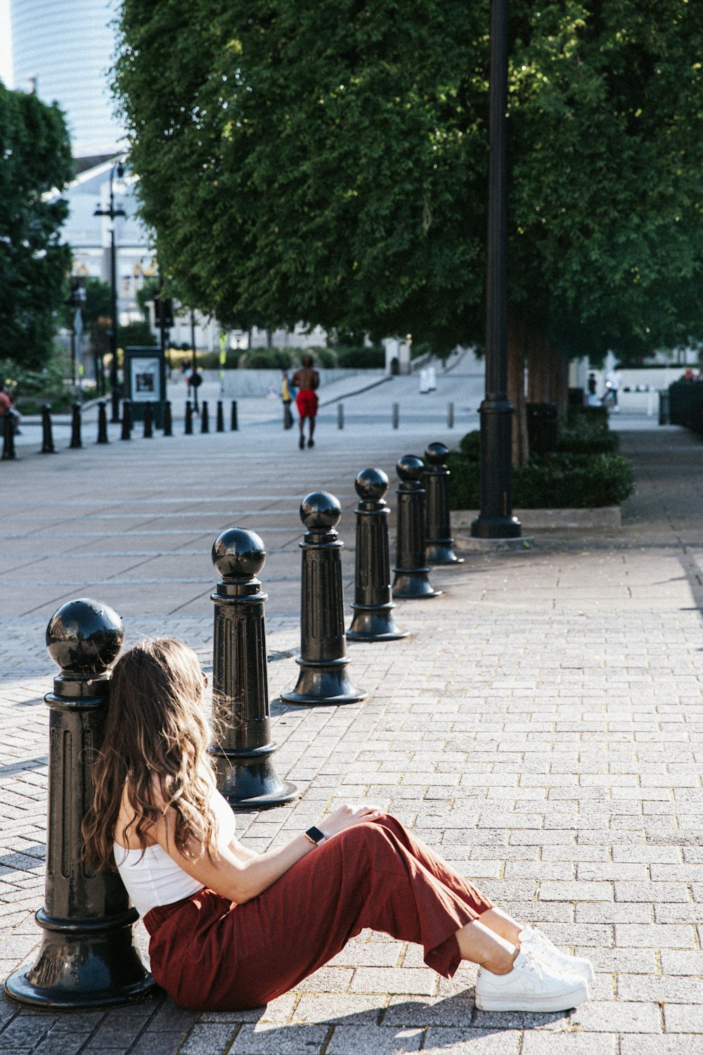 woman in red jacket sitting on bench during daytime