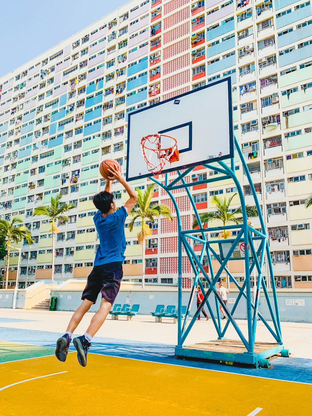 homem de camisa azul e calção preto jogando basquete durante o dia