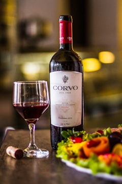 a plate of salad next to a bottle of wine