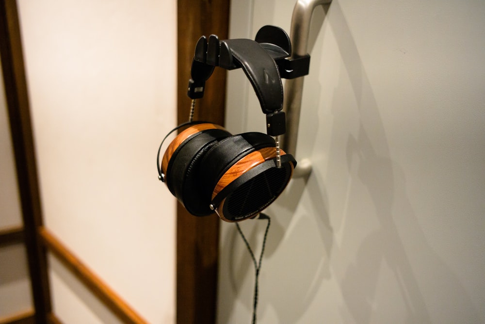 black and silver headphones hanging on white wall