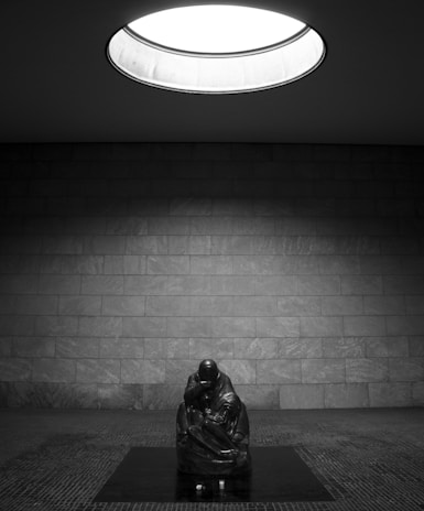 A photograph capturing a sculpture reflecting on human condition with shadow play.
