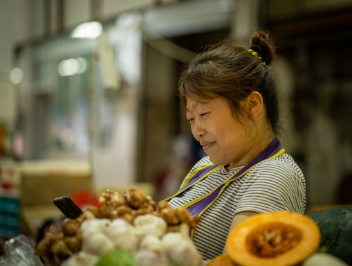 A friendly farmer holding fresh produce with a smartphone in hand, smiling warmly.