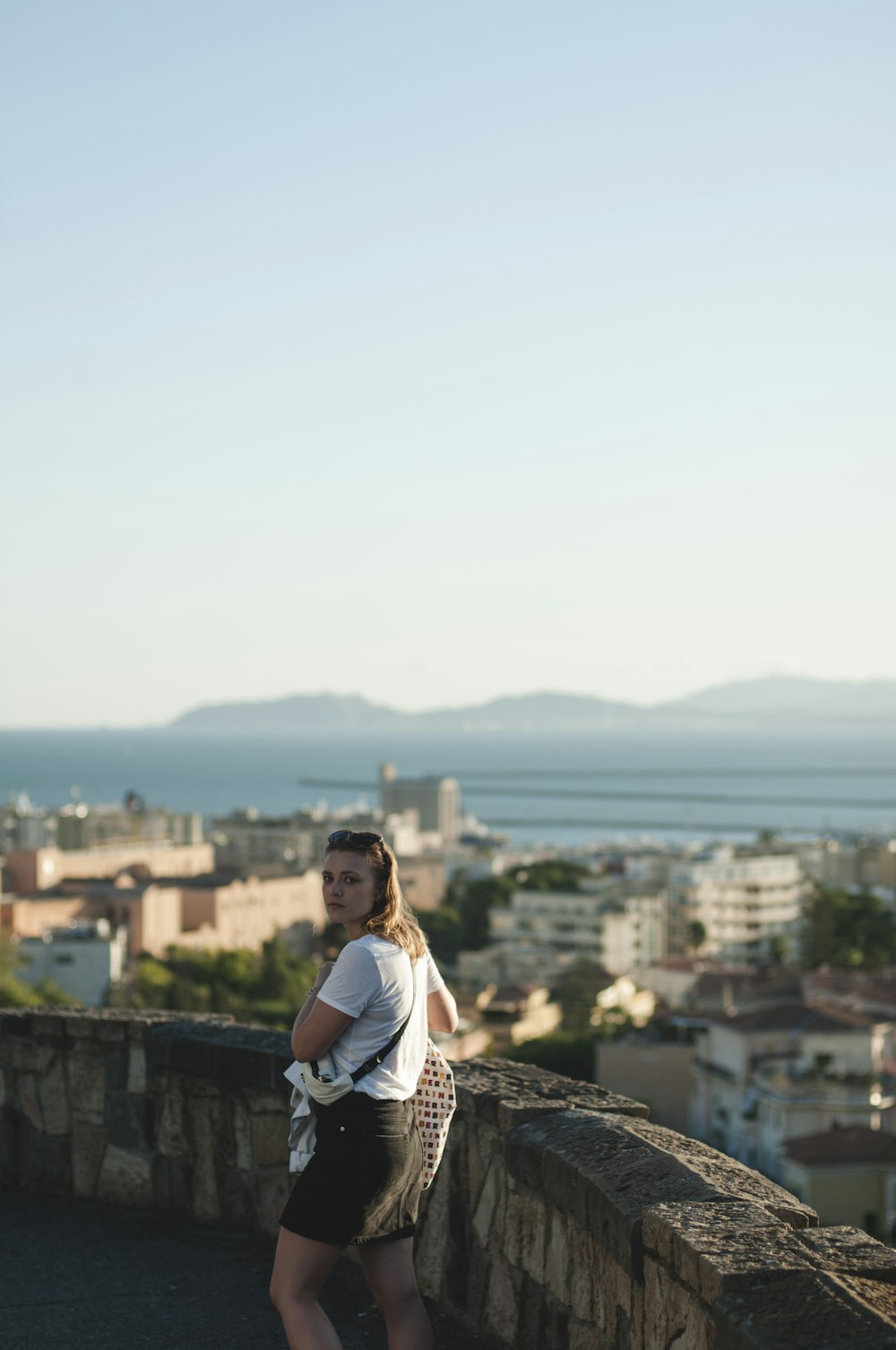 woman in white shirt sitting on the roof top during daytime