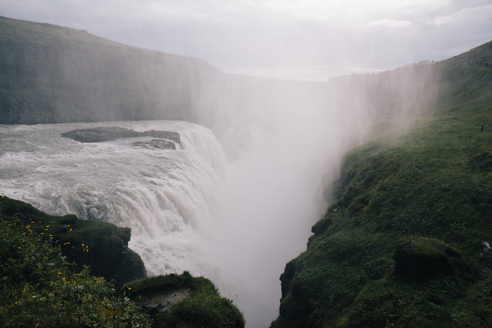 cascades sur la montagne couverte d’herbe verte pendant la journée