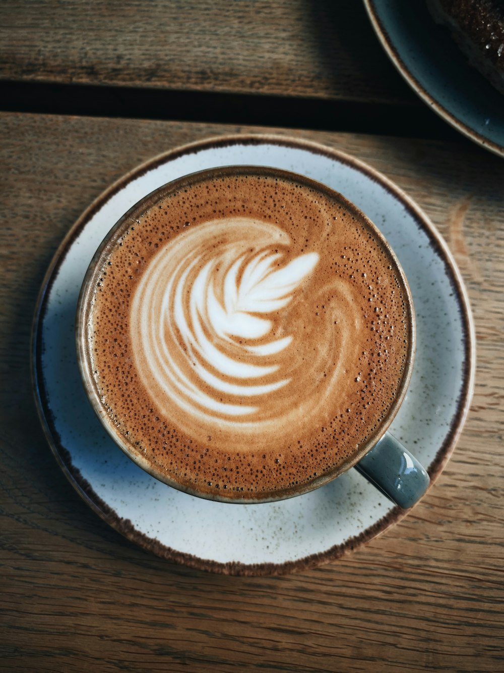 Tasse en céramique blanche avec soucoupe sur table en bois brun