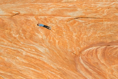 man in black shirt and blue denim jeans standing on brown sand