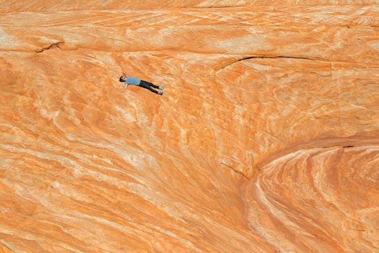 man in black shirt and blue denim jeans standing on brown sand