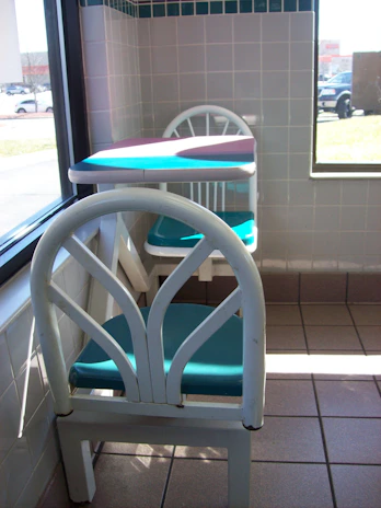 A bright, compact nook corner dining table set with colorful stackable resin stools in a sunlit kitchen.