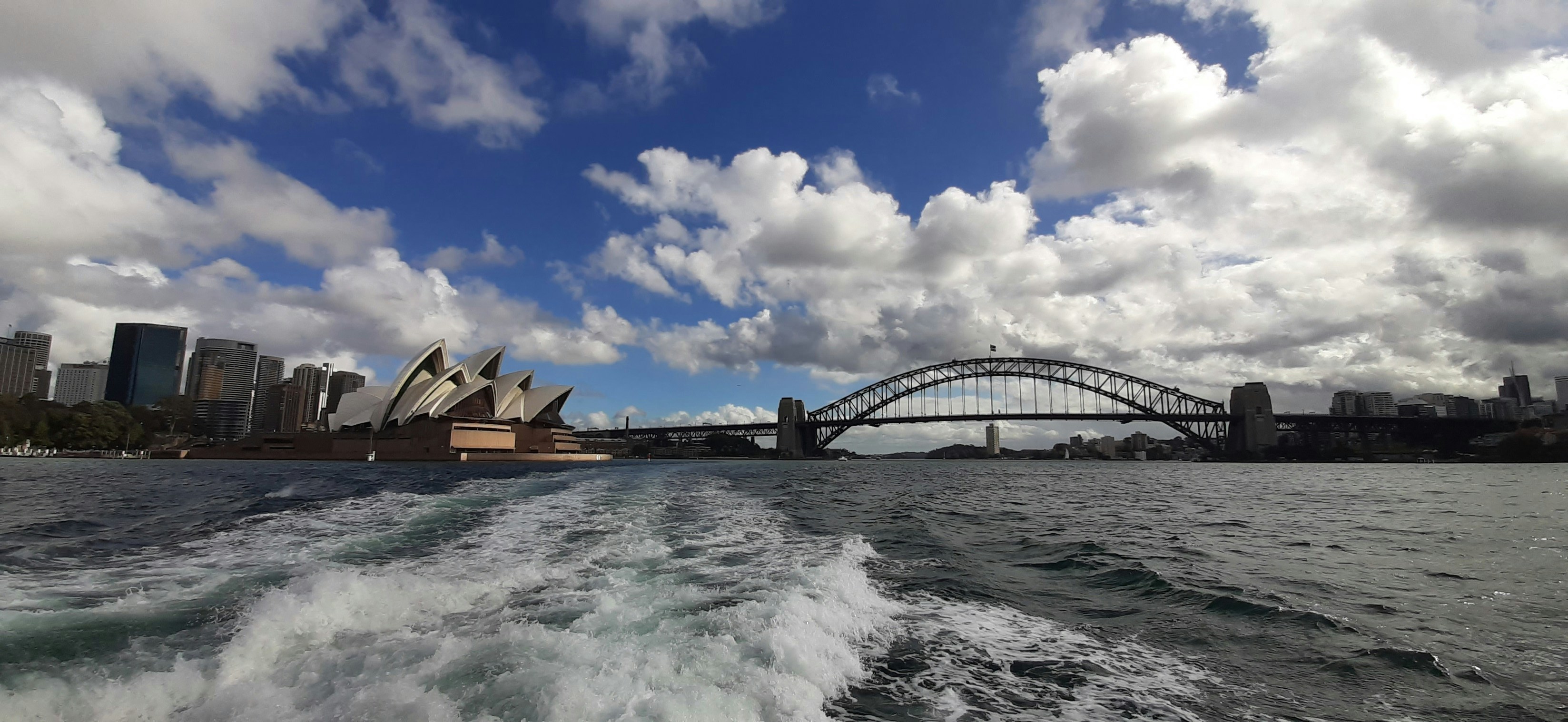 brown wooden bridge over water under blue sky and white clouds during daytime