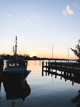A beautifully crafted dock with a boat lift, set against a calm waterfront at sunset.