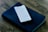 A smartphone displaying text on its screen is placed on top of a closed, black, leather-bound book, which appears to be a Bible. The setup is on a wooden surface, giving a rustic and serene ambiance.