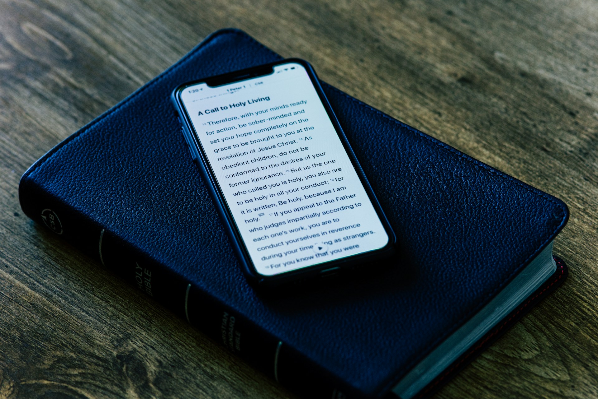A close-up of hands holding a Bible alongside a tablet displaying a Christian film, blending tradition with technology.