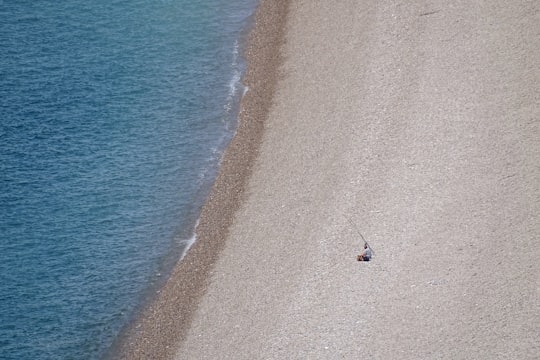 person in black shirt standing on seashore during daytime in Chesil Beach United Kingdom