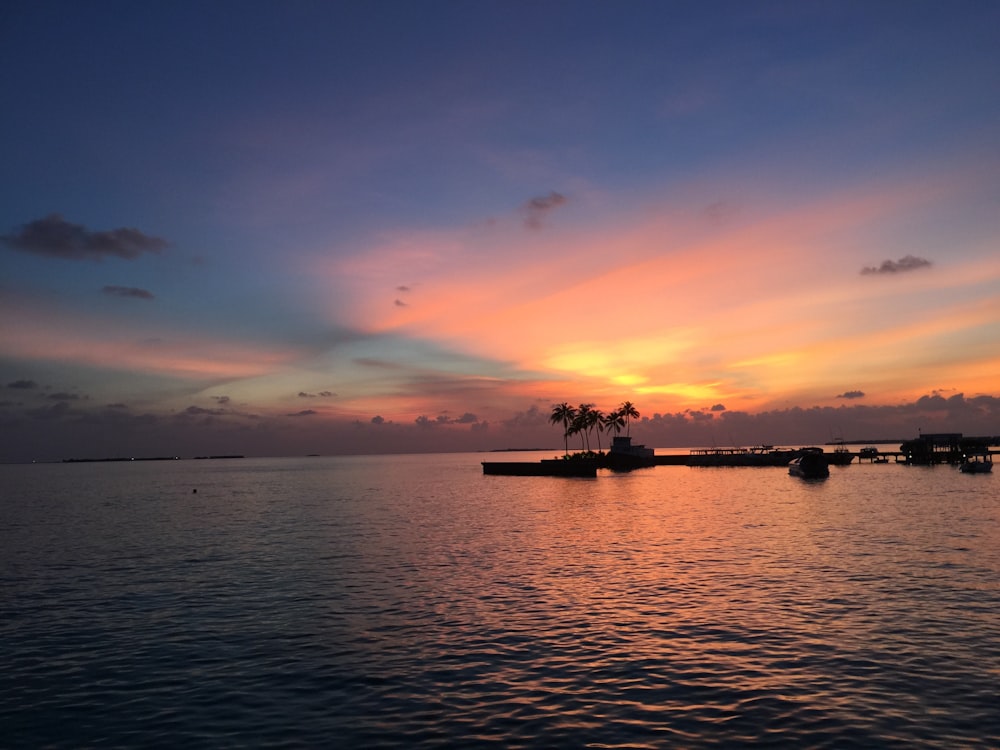 silhouette of boat on sea during sunset