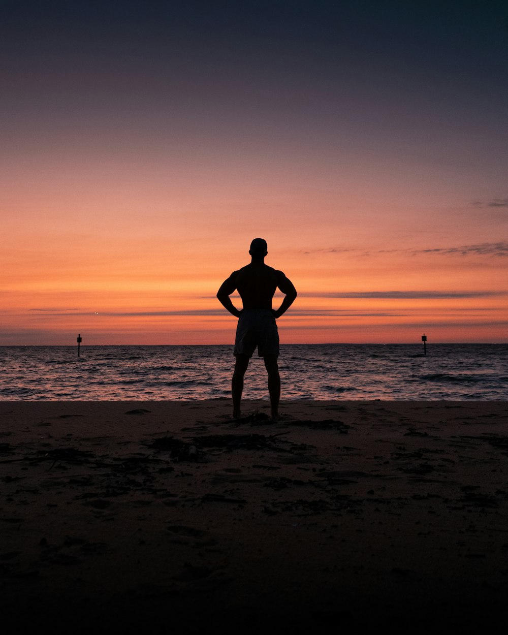 Silhouette von Mann und Frau, die bei Sonnenuntergang am Strand stehen