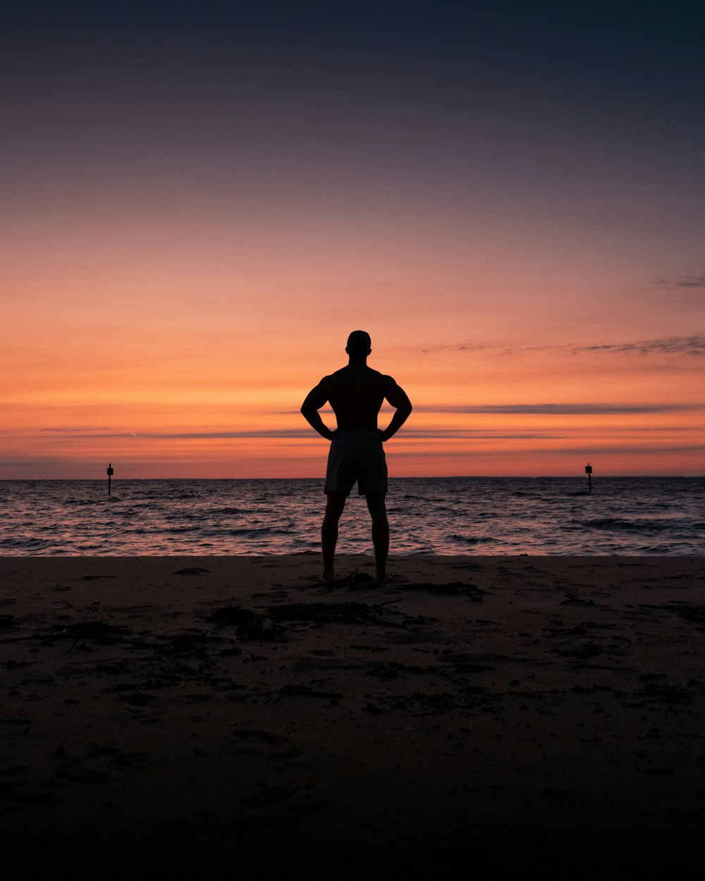 silhouette of man and woman standing on beach during sunset