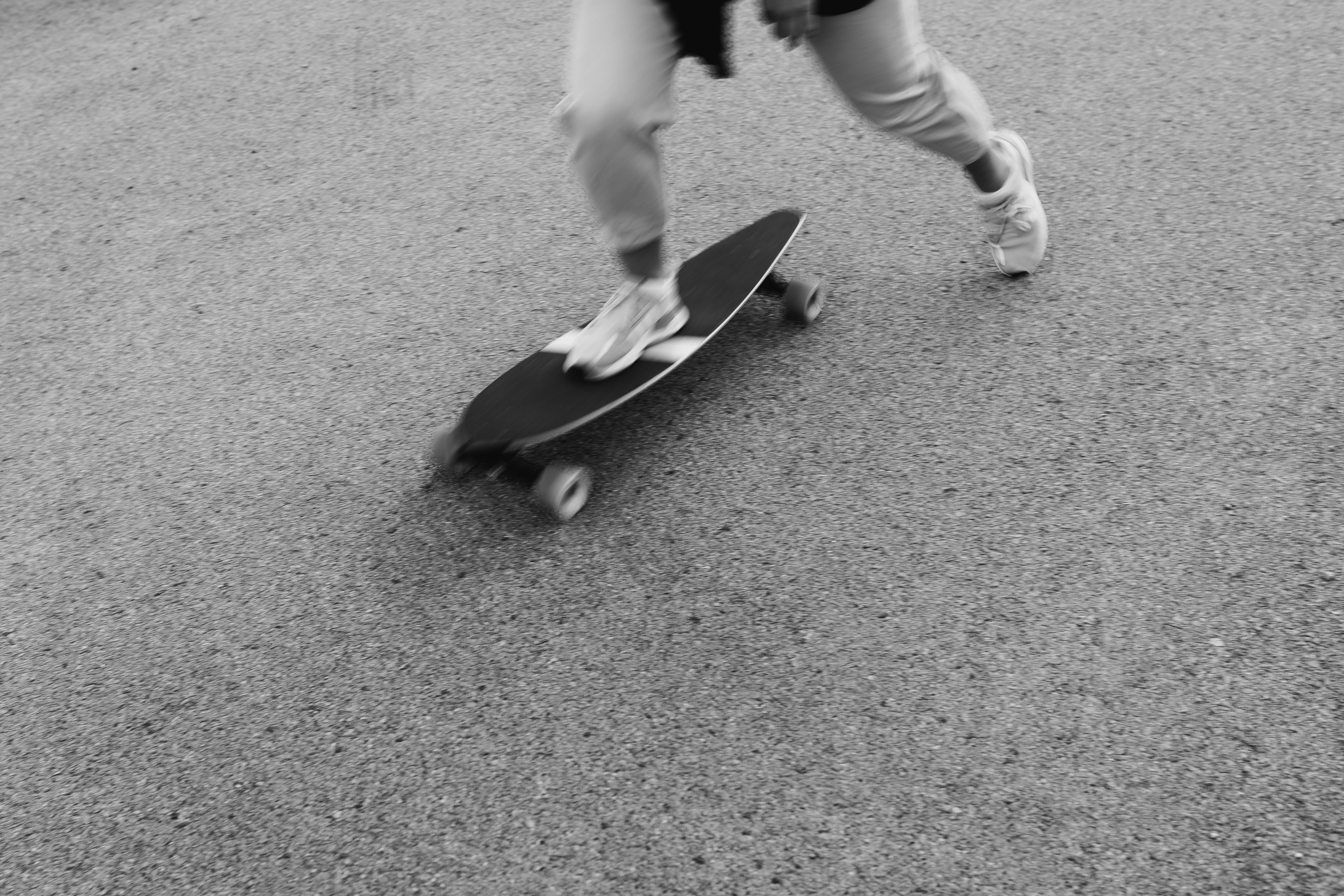 person in white pants and black shoes holding black skateboard