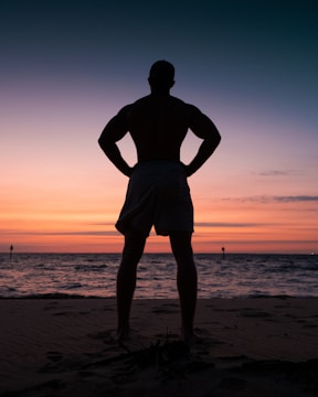 silhouette of man standing on beach during sunset