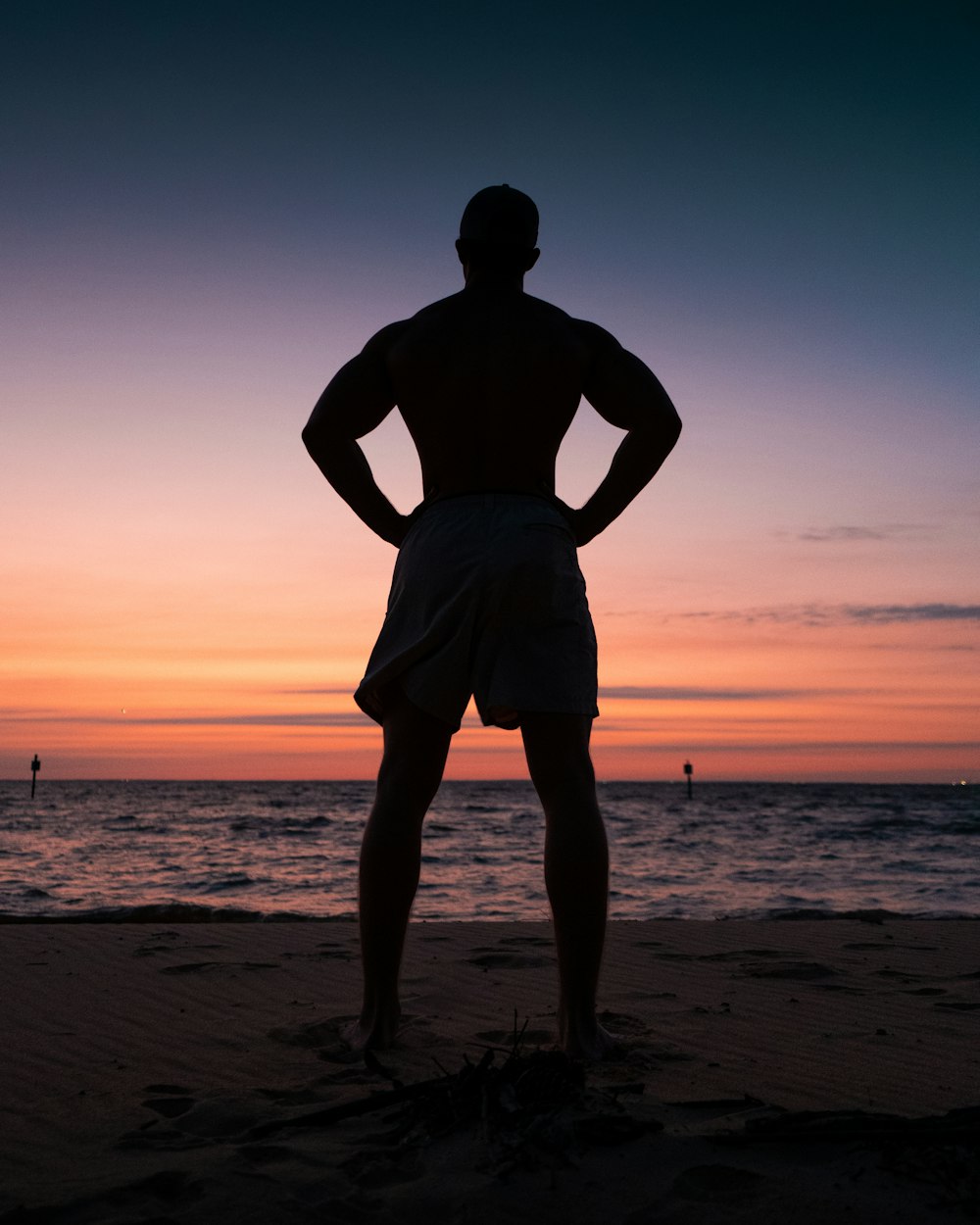 夕暮れ時の浜辺に立つ男のシルエット