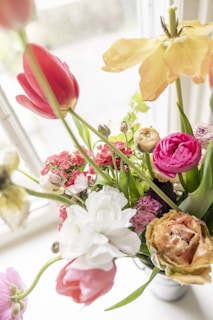 A close-up of a vibrant bouquet with roses and wildflowers in a clear glass vase.