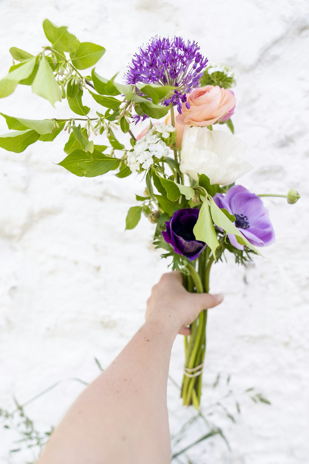 보라색과 흰색 꽃을 들고 있는 사람