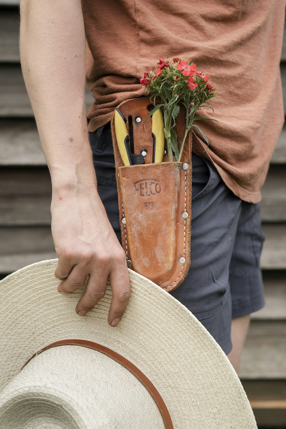 person in brown long sleeve shirt holding green plant