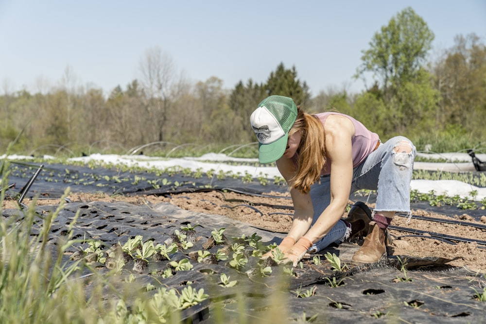 Femme en chemise rose et jean bleu assis sur un rocher brun près de la rivière pendant la journée