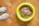 A pair of dog paws on a wooden floor next to a yellow bowl filled with raw dog food.