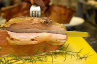 A chef slicing a juicy Chateaubriand roast with precision in a warmly lit kitchen.