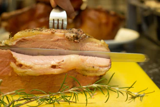 A chef slicing a juicy Chateaubriand roast with precision in a warmly lit kitchen.
