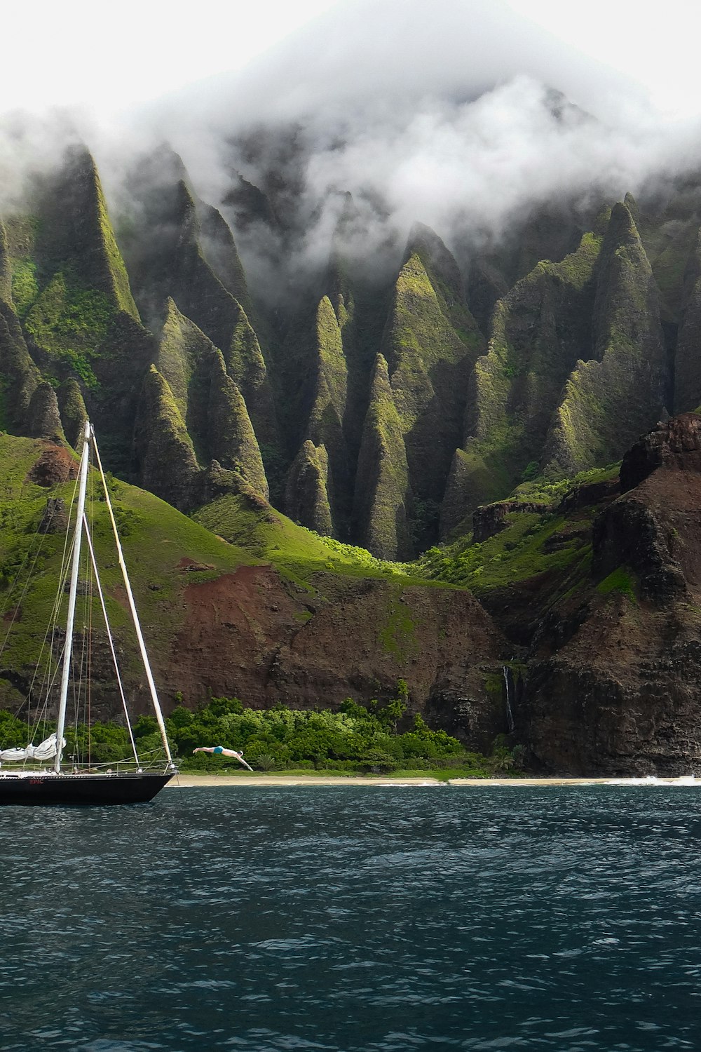 white sail boat on body of water near mountain during daytime