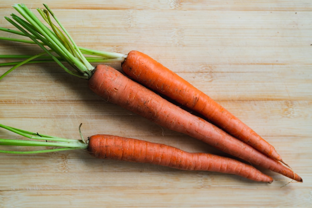 3 carrots on brown wooden table