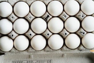 Close-up of a carton filled with fresh, clean eggs on a white background with blue accents.