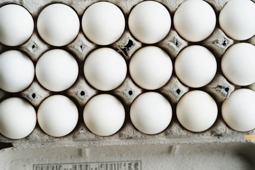 Close-up of hands carefully packing fresh eggs into cartons inside a warehouse