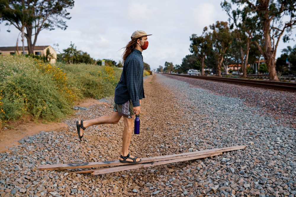 woman in blue denim shorts and blue denim jacket walking on train rail during daytime