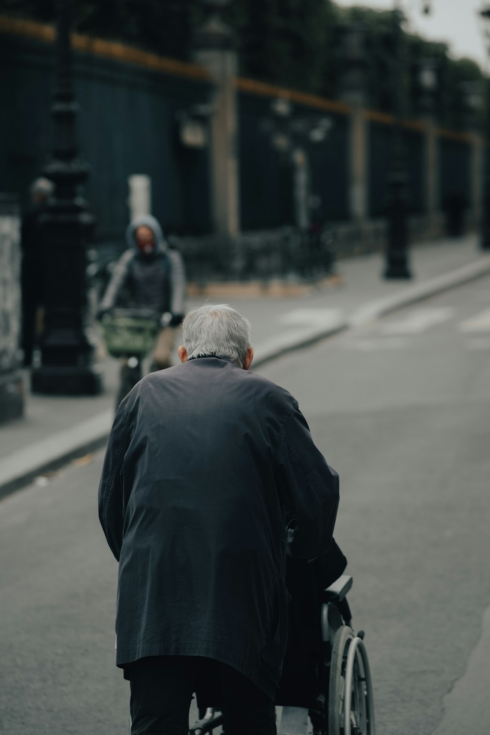 昼間、道路に立つ黒いジャケットの男