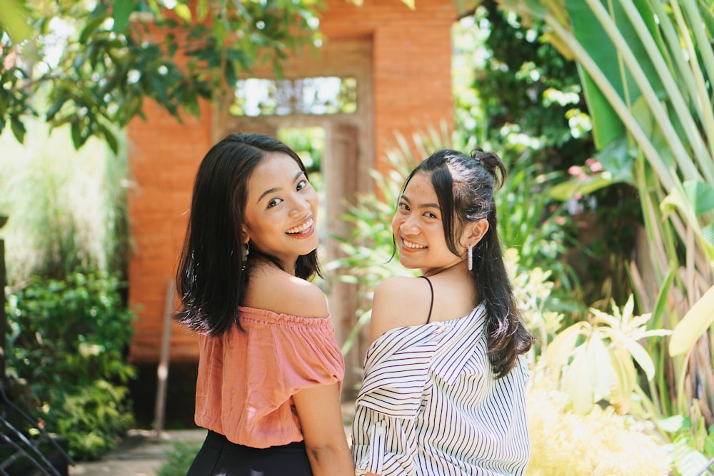 2 women standing near green leaf plants during daytime