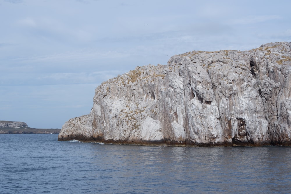 brown rock formation on sea under white clouds during daytime