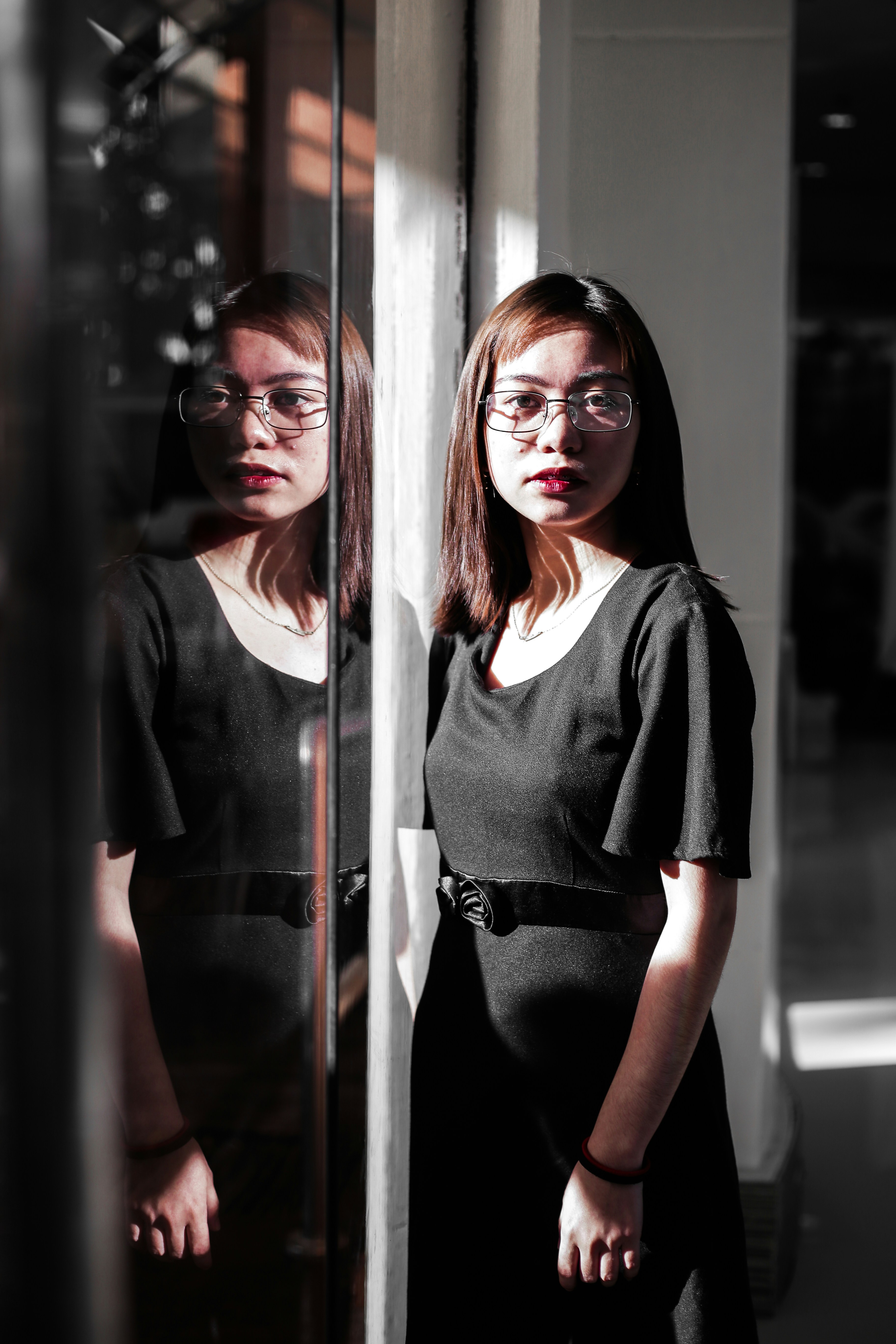 Femme en blazer noir debout à côté d’une fenêtre en verre