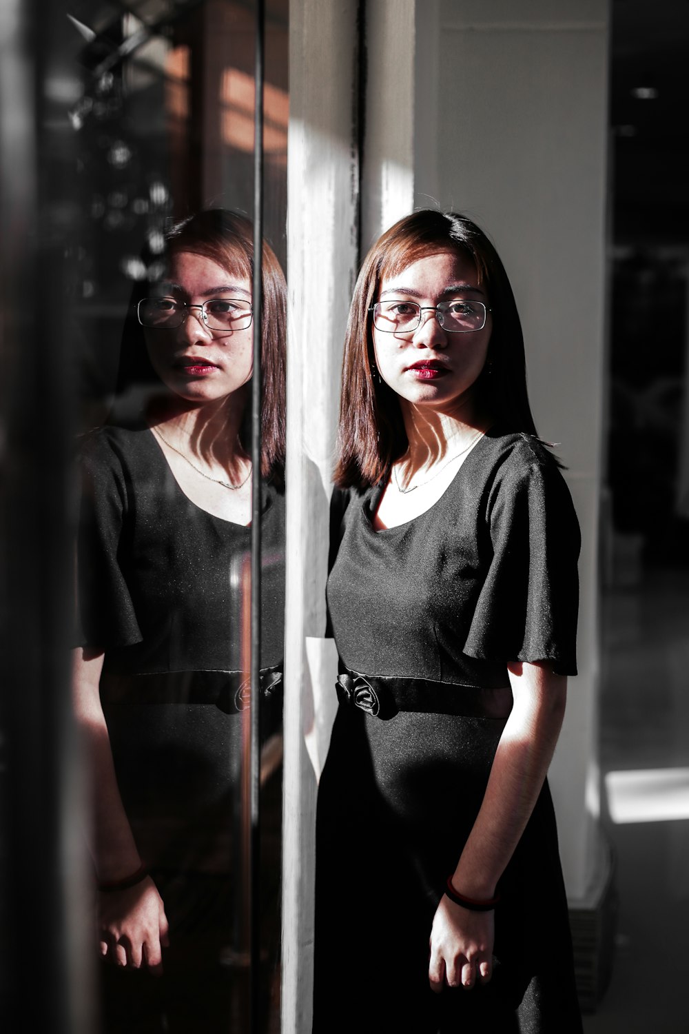 woman in black blazer standing beside glass window