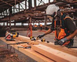 man in orange and black vest wearing white helmet holding yellow and black power tool