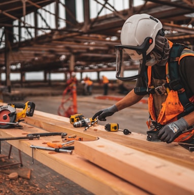 man in orange and black vest wearing white helmet holding yellow and black power tool