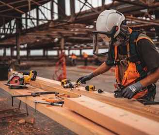 man in orange and black vest wearing white helmet holding yellow and black power tool