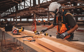 man in orange and black vest wearing white helmet holding yellow and black power tool