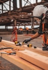 man in orange and black vest wearing white helmet holding yellow and black power tool